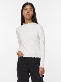 Biała, prążkowana bluzka z długim rękawem i falbaniastym dekoltem oraz wykończeniem, prezentująca dopasowany krój i teksturowany materiał. Noszona z czarnymi spodniami.