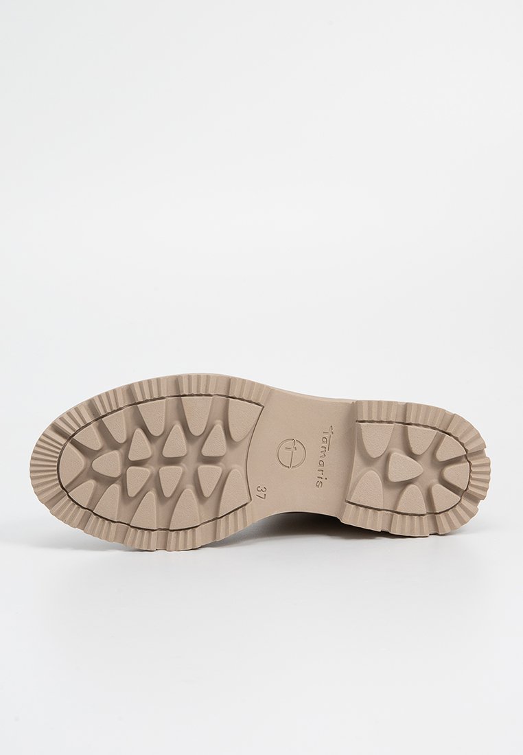 Beige Gummi Schuhsohle mit strukturiertem Profil, das dreieckige und runde Formen aufweist. Seitlich mit Logo und Größe 37 gekennzeichnet.