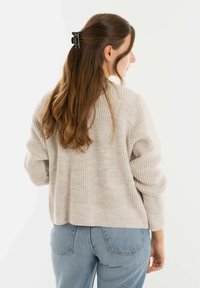 Lichtgrijze gebreide sweater met een losse pasvorm, geribbelde textuur en verlaagde schouders. Draag het met hooggelegen blauwe jeans.