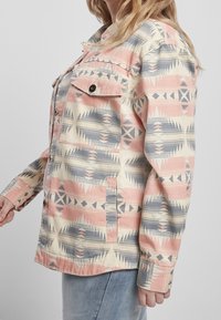 Mønstret jakke med pastelfarve skema i rosa, creme og blå. Har krave, knapper, to brystlommer og lange ærmer.