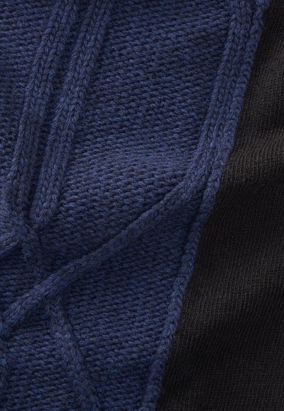 Close-up of navy blue knitted fabric with raised textured pattern next to smooth black knitted fabric.