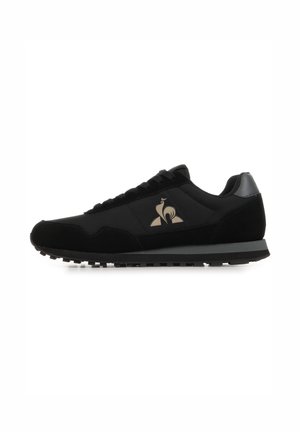 Black low-top sneaker with lace-up front, textured sole, and a beige rooster logo on the side.