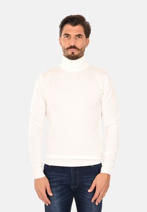 Maglione bianco a collo alto con un design aderente, realizzato in un tessuto morbido con polsini e orlo a coste, abbinato a jeans blu scuro.