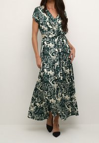 Grön och gräddfärgad marmorvirkad maxiklänning med en omslagdesign, korta ärmar och knytvad. Har en svävande kjol. Bärs med svarta skor.