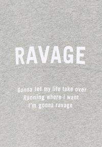 Grå t-shirt med fet vit text som lyder "RAVAGE" och ytterligare textrader i mindre stil. Mjuk bomullsmaterial, avslappnad passform.