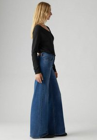 Wijde blauwe denim jeans met een hoge taille, met een klassiek vijf-pocket ontwerp en een medium wassing. Zachte textuur met vervaagde accenten.