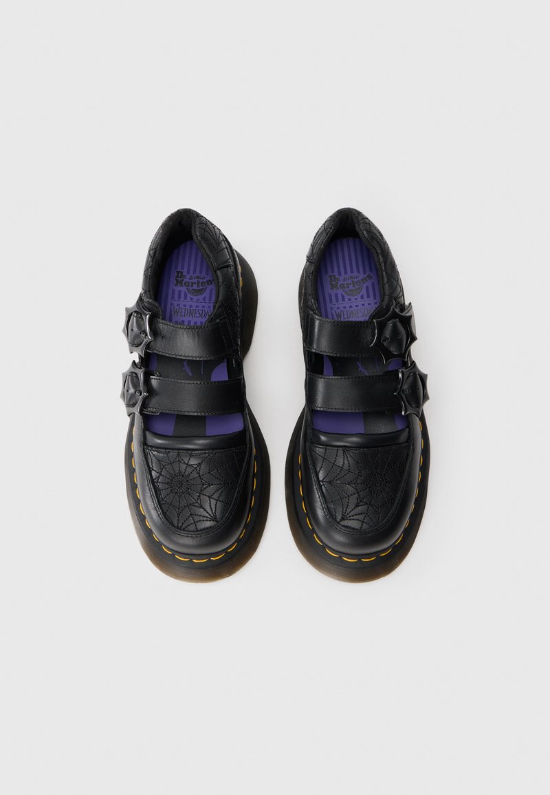 Chaussures Mary Jane en cuir noir avec doubles sangles et boucles en forme d'étoile, ornées de surpiqûres en toile d'araignée et de semelles intérieures violettes avec marquage.