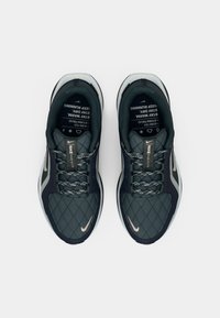 Ciemnoszare buty sportowe z pikowanym wierzchem, z odblaskowymi akcentami i wzorzystymi sznurowadłami. Posiadają amortyzowaną podeszwę oraz logo Nike.