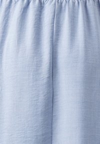 Ljusblått tyg med en mjuk, strukturerad yta, med en rynkad midjeresår och ett jämnt fall. Inga tydliga mönster eller detaljer är synliga.