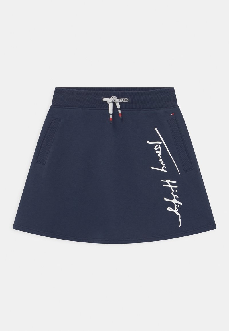 Navyblauwe rok met zijzakken, trekkoord taille met merksleutels, en witte "Tommy Hilfiger" scriptlogo aan de rechterzijde.