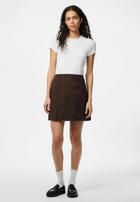Chemise blanche à manches courtes associée à une jupe A-line marron. Les accessoires comprennent des chaussures noires et des chaussettes blanches. Textures simples et lisses.