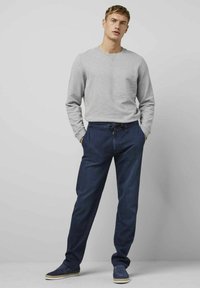 Sweatshirt gris à manches longues associé à un pantalon ample bleu marine avec une taille élastique et un cordon de serrage.