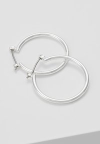 Silver hoop earrings with a polished finish, featuring a circular shape and a secure hinge closure. Lightweight and minimalistic design.