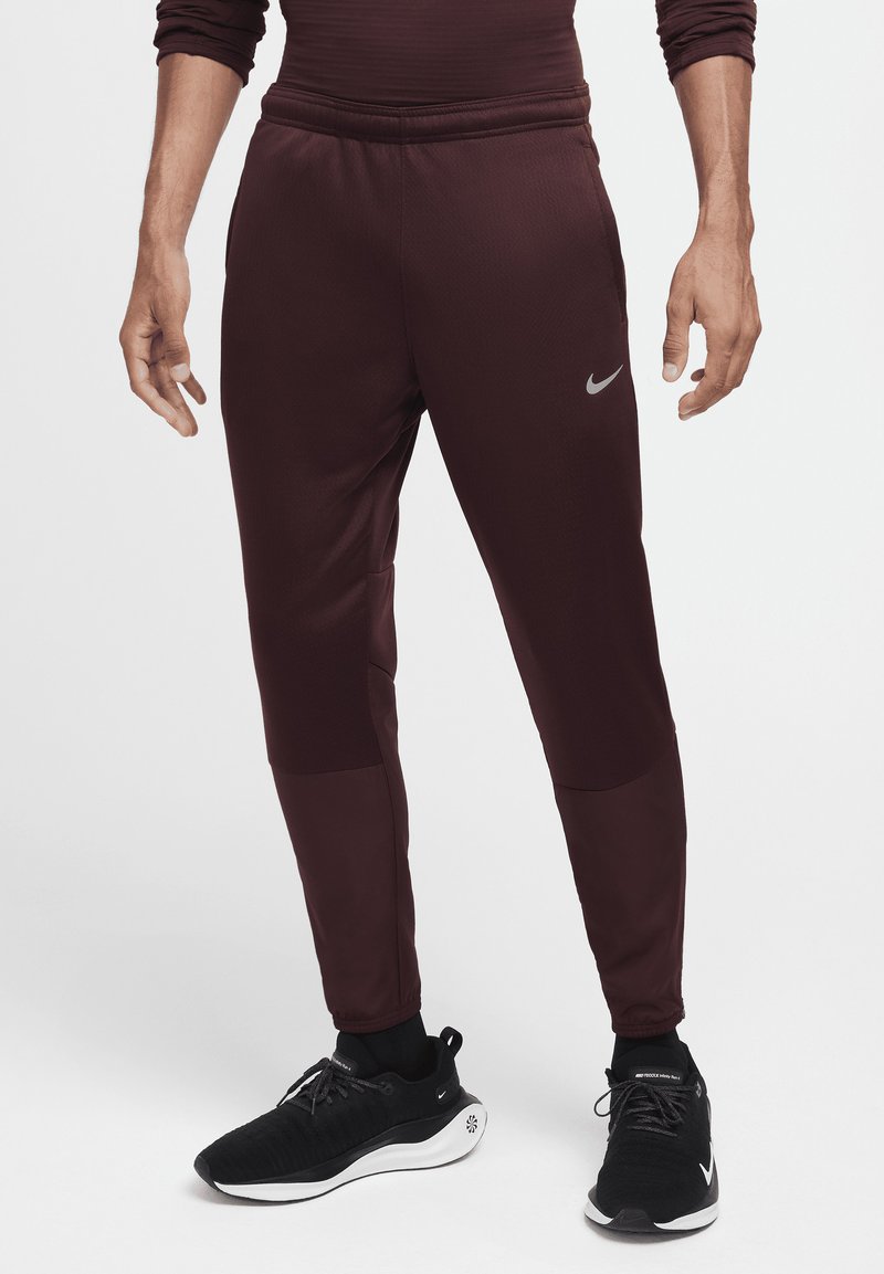 Burgundowe spodnie sportowe o zwężanym kroju, wykonane z teksturowanej tkaniny, z elastycznym pasem i kieszeniami po bokach. Zawierają mały akcent w postaci logo.