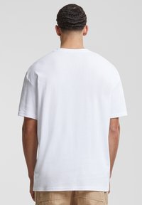 Tricou alb din bumbac, cu un croi lejer, mâneci scurte și un decolteu rotund, având o textură fină și fără modele vizibile.