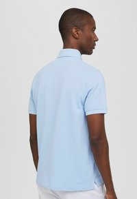 Jasnoniebieska koszulka polo z krótkim rękawem, z klasycznym kołnierzykiem, miękką teksturą i bocznymi rozporkami dla swobody ruchów.