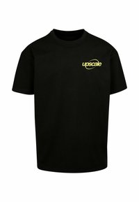 T-shirt en coton noir à manches courtes et col rond. Présente un logo jaune "upscale" sur le côté gauche de la poitrine. Design simple.