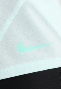 Top sportivo azzurro chiaro realizzato in tessuto liscio, con logo Nike swoosh verde menta e bordi neri a contrasto nella parte inferiore.