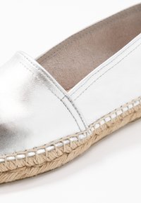 Srebrna metalik espadrila s glatkim kožnim gornjištem, prošivenim rubom i prirodnom jutenom espadrilskom petom.