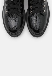 Sneaker in pelle lucida nera con texture a coccodrillo, dotate di occhielli metallici, lacci neri e una suola in gomma spessa.