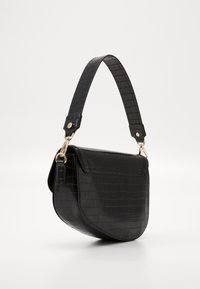 Svart fusk läder crossbody-väska med krokodilmönster, böjd silhuett, avtagbar rem och detaljer i guldfärg.