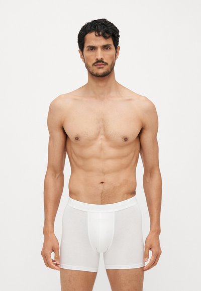 Boxer shorts brancos em algodão com um design ajustado, cintura elástica com detalhe do logótipo, textura suave e um bolso contornado.