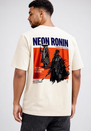 Mann trägt ein hellbeiges T-Shirt mit einer Grafik von zwei futuristischen Samurai-Kriegern und den Texten "NEON RONIN" und "Way of the Chrome Warrior" auf dem Rücken.