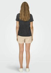 Donkergrijze t-shirt met korte mouwen en een relaxed fit, gecombineerd met lichtbeige textuurshorts en witte sneakers. Achteraanzicht weergegeven.