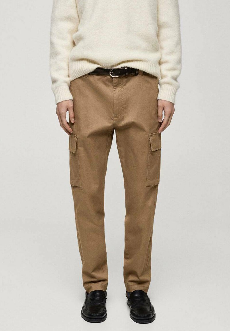 Beige cargo kalhoty s dvěma bočními kapsami, vyrobené z bavlny, s rovnou siluetou a volným střihem. Nosené s bílým pleteným svetrem.