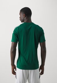 Groen sportshirt van ademend materiaal, met korte mouwen, een ronde hals en contrasterende witte accenten op de schouders.