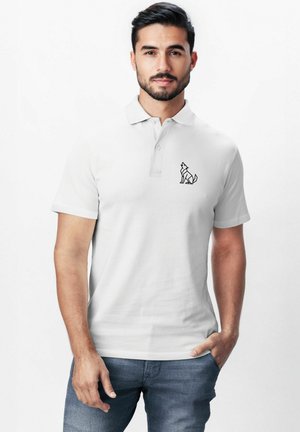 Weißes Poloshirt aus Baumwolle mit Kragen und kurzen Ärmeln. Auf der linken Brust befindet sich eine schwarze Wolfssilhouette als Stickerei.
