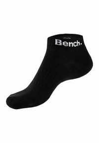 Schwarze Knöchel-Socken aus weichem Stoff, mit gerippter Textur und einem weißen "Bench."-Logo am Bündchen. Mittlere Höhe bis zur Wade, taillierte Passform.