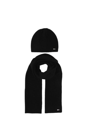 Black knitted hat and matching long scarf laid flat on a white background, each with a small rectangular metal logo tag.
