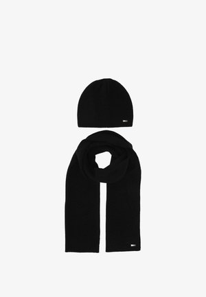 Black knitted hat and matching long scarf laid flat on a white background, each with a small rectangular metal logo tag.