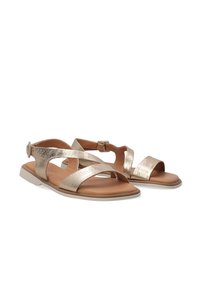 Gouden metallic sandalen met kruislussen en een achterste gesp. Glad bruine binnenzool met een platte, lichte rubberen zool. Verstelbare pasvorm.