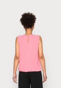 Růžová bezramínková blůza s kulatým výstřihem a otvorem ve tvaru klíče na zadní straně, s nařaseným lemem pro volný střih.