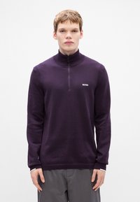 Μωβ ζιπ-νεκ πουλόβερ με ribbed κολάρο και μανσέτες. Διαθέτει διακριτό λογότυπο στο στήθος. Μαλακό ύφασμα με ομαλή υφή, σε συνδυασμό με γκρι παντελόνι.