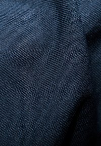 Tessuto blu scuro con una trama texture, che mostra un primo piano della superficie, mettendo in evidenza le sue caratteristiche morbide e durevoli.