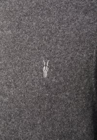 Šedý vlněný svetr s jemným, texturovaným povrchem a diskrétním vyšitým logem v světlejším odstínu. Jednoduchý design, bez vzorů nebo akcentů.
