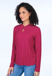 Langarmshirt in Dunkelrosa mit helleren rosa Punkten, mit einem Schlüsselloch-Ausschnitt und einer lockeren Passform. Glattes Material, lässiges Design.