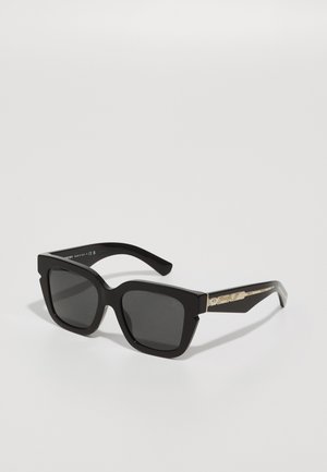 Black square sunglasses with thick frames, dark lenses, and metallic accents on the temples feature a unique geometric design.