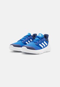 Baskets de sport bleues en mesh et matériaux synthétiques, avec un design à trois bandes blanches, un col rembourré et une semelle blanche amortissante.