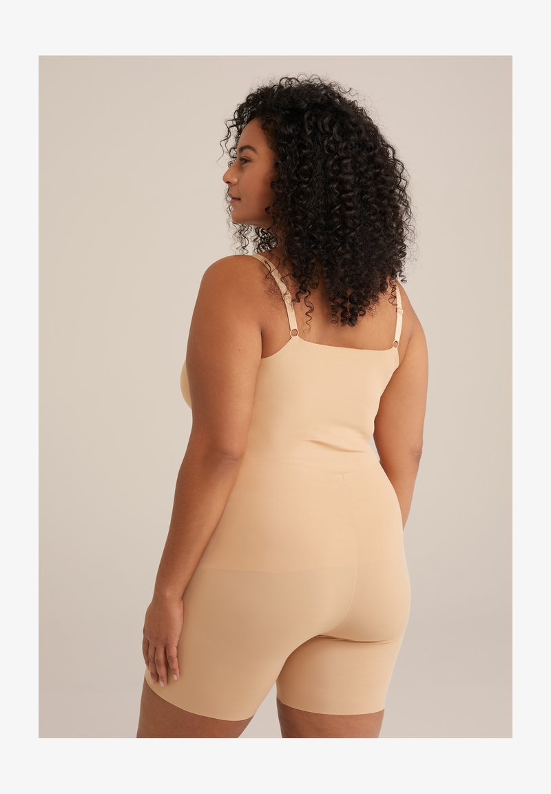 Nuogo bodysuit su reguliuojamomis petnešomis, prigludusi dizaino ir švelniomis tekstūra. Ilgis iki vidurinio šlaunies. Sukurtas komfortui ir palaikymui.