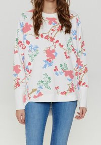 Blommig sweatshirt med långa ärmar, vit bakgrund, med rosa, blå och gröna blommiga mönster. Avslappnad passform och rund halsringning.
