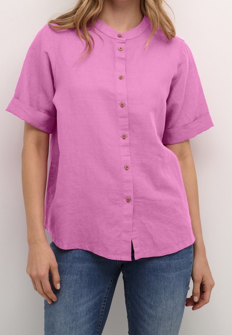 Kortärmad, knäppt skjorta i ljusrosa linne, med rund halsringning, lätt struktur och träknappar framtill.
