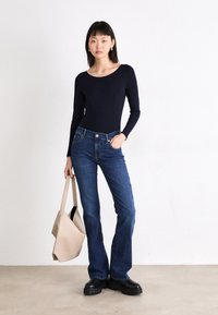 Marine langermet topp, mørkeblå vide jeans, svarte platåsko og en beige tote bag. Glattstoff og tettsittende design.