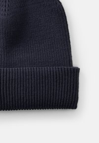 Knit beanie in dark navy, featuring ribbed texture and a folded cuff. Material appears soft with a consistent pattern throughout.