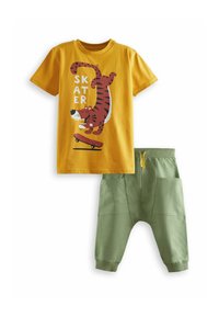 Gul bomulds t-shirt med tiger grafik og "SKATER" tekst; parret med grønne joggerbukser med elastisk talje og sidelommer.