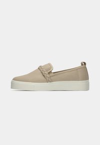 Beige slip-on shoes with a braided accent, made of canvas, featuring a thick white sole and a pull tab at the heel.