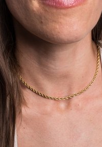 Collana girocollo in oro a spirale con una finitura liscia e lucida. Maglie testurizzate formano un design continuo. Si adagia aderente attorno al collo.